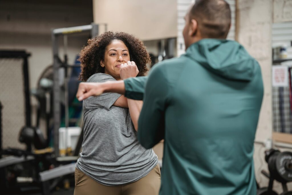 Trainer warming up with black woman in gym